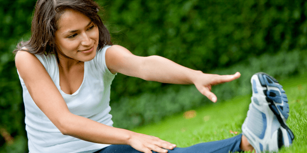 woman stretching her leg on grass
